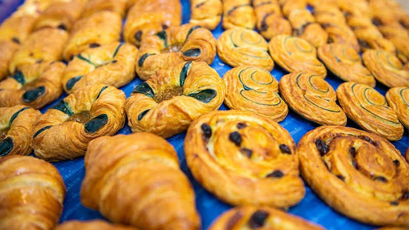Pastries like croissants and snails are spread out on a blue surface.