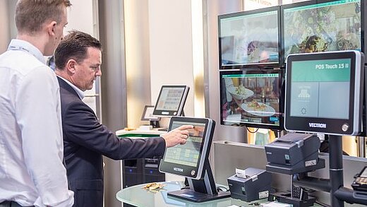 Zwei Männer stehen vor mehreren Bildschirmen und erkunden die Technik