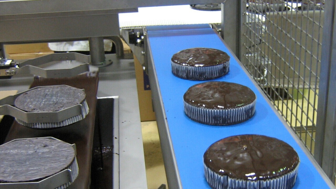 Dipping of 2" cup cakes into a glaze bath