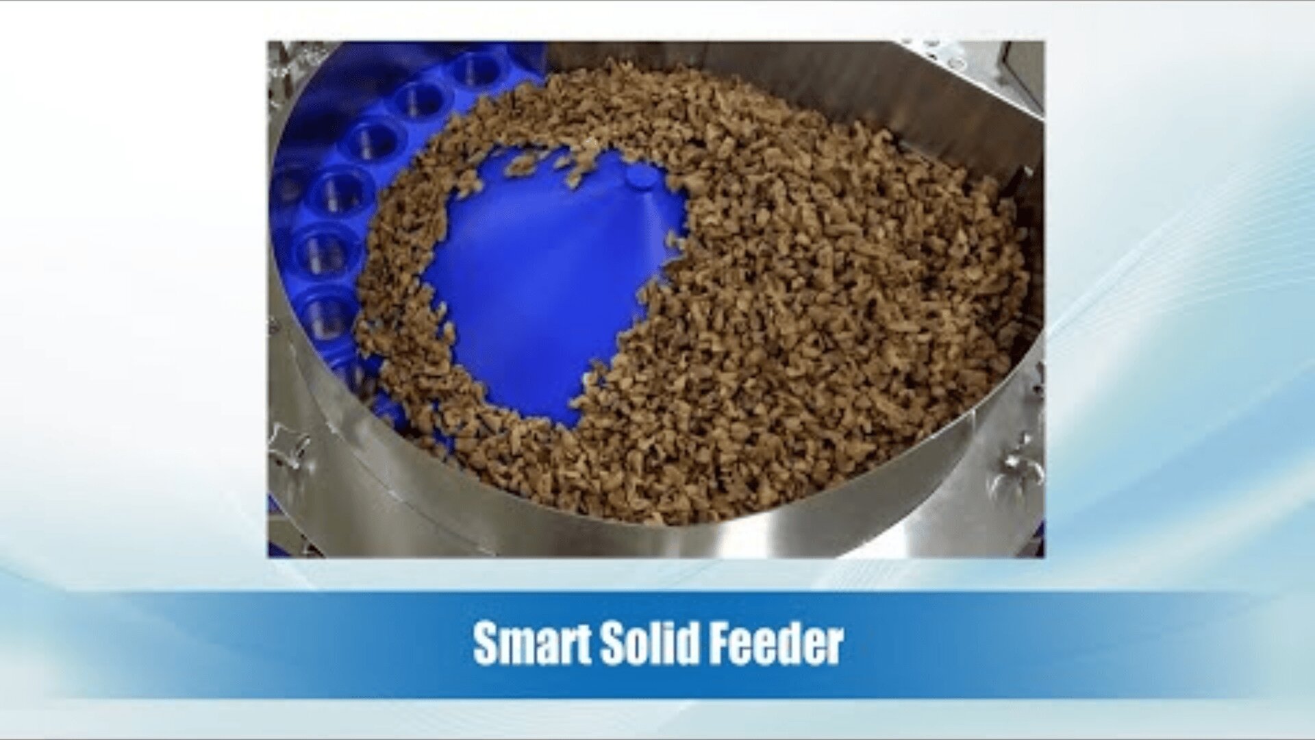 Close-up of a metal Smart Solid Feeder filled with brown solid pellets arranged in a circular pattern on a blue tray. The text below the image reads Smart Solid Feeder.