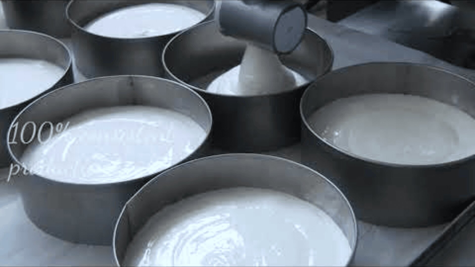Cake batter being poured into multiple round metal baking pans, filling them evenly in preparation for baking.