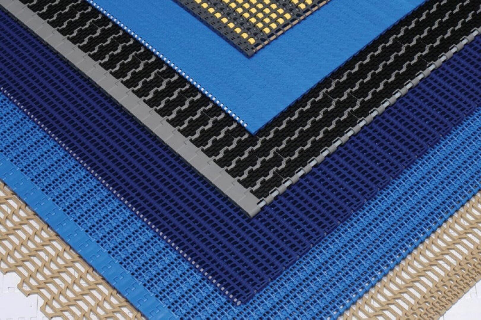 A close-up of overlapping modular plastic conveyor belts in various colors and patterns, including blue, black, grey, beige and yellow, arranged in a fan-like configuration.