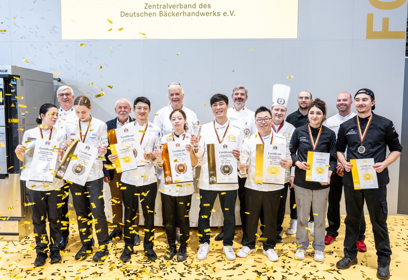 Siegerehrung des iba.UIBC CUP of Confectioners 2023 auf der Bühne des iba.FORUM. Gruppenbild mit allen Organisatoren, Jury-Mitgliedern und den Teilnehmern – Team Süd Korea, Team, Norwegen, Team Deutschland und Team Taiwan.