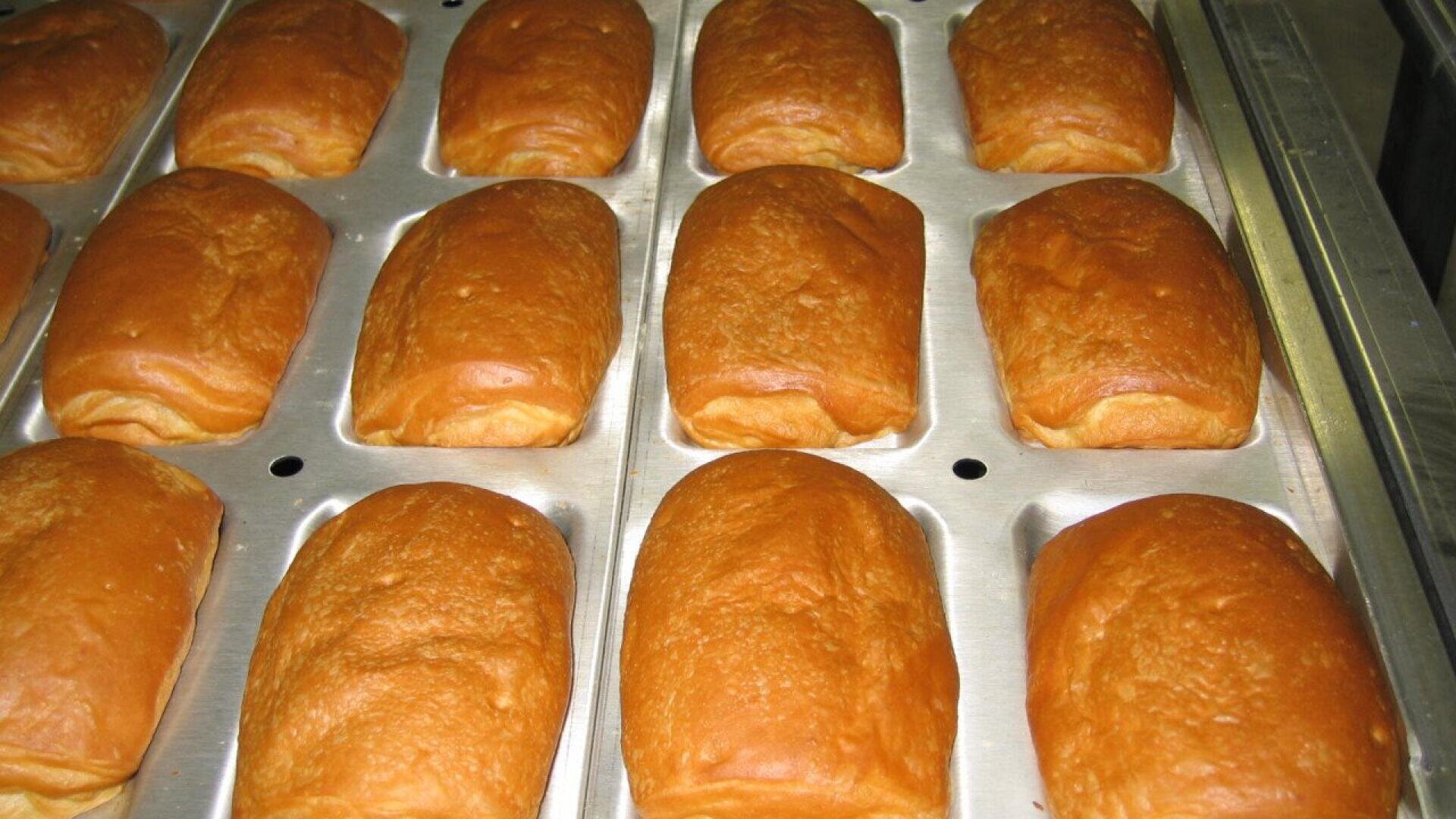 Goldbraune Brötchen, ordentlich in einem Metallblech angeordnet, frisch aus dem Ofen und bereit, serviert zu werden.