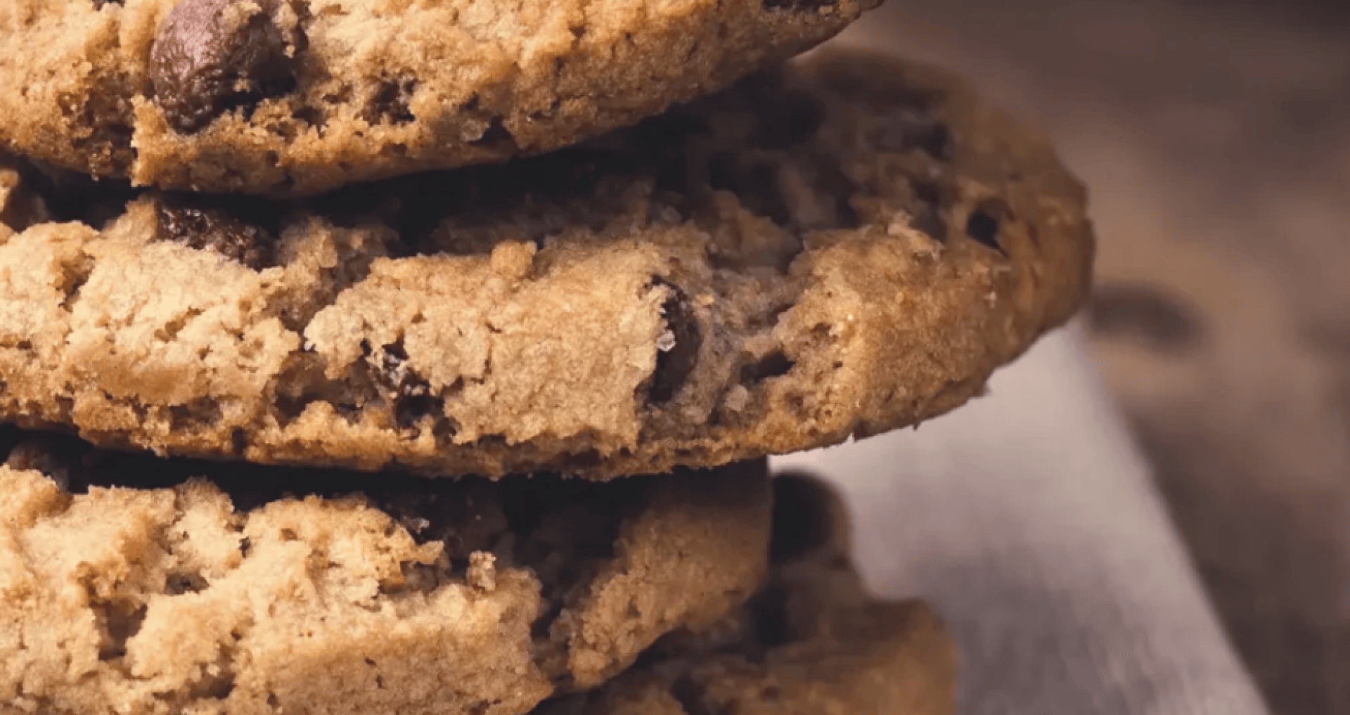 A close-up of a stack of chocolate chip cookies on a napkin, showing the crumbly texture and chocolate chips.