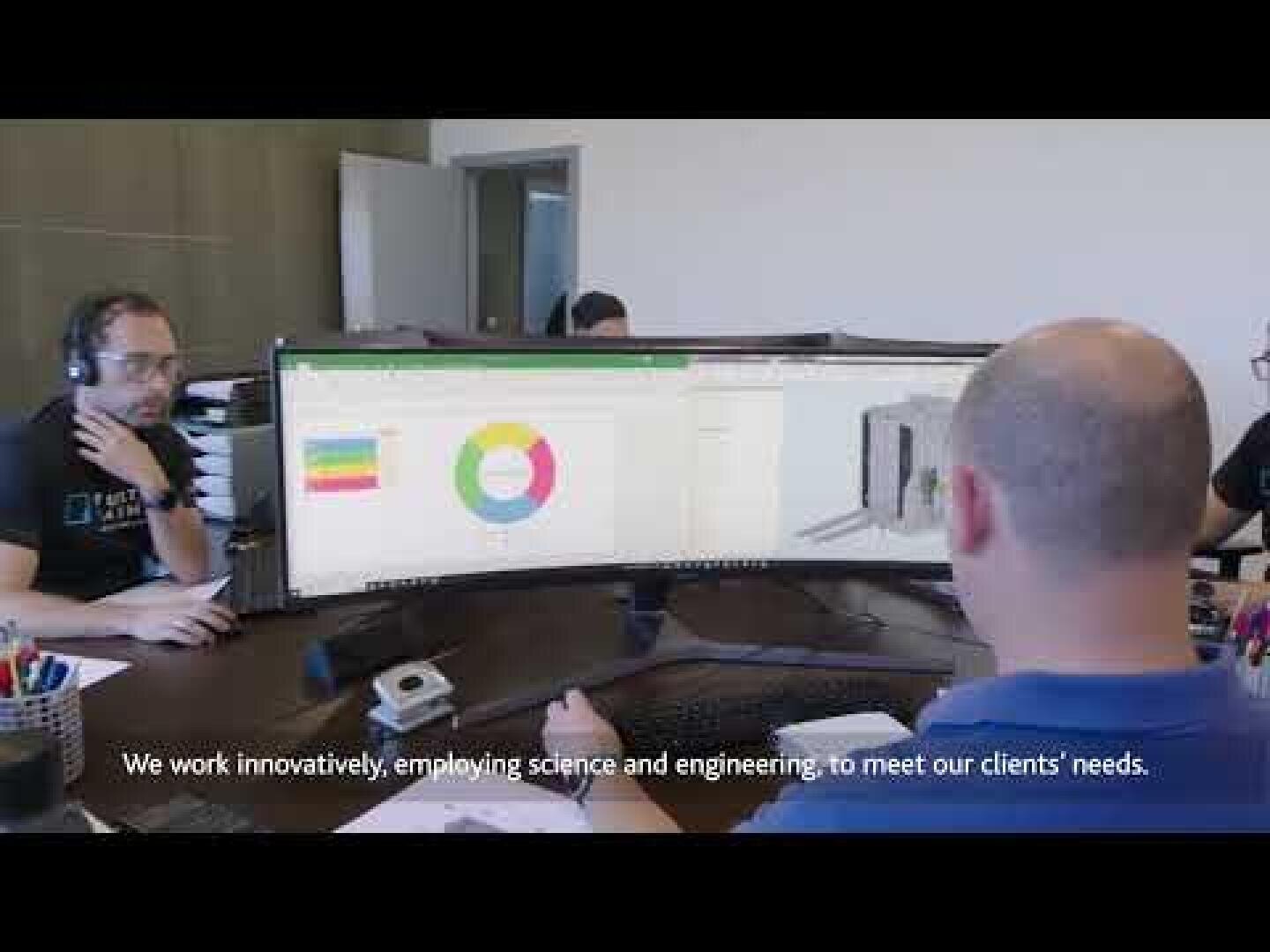 Zwei Personen sitzen an einem Schreibtisch mit großen gebogenen Monitoren, auf denen Diagramme und 3D-Konstruktionen zu sehen sind. Der Untertitel lautet: "Wir arbeiten innovativ und setzen Wissenschaft und Technik ein, um die Bedürfnisse unserer Kunden zu erfüllen.