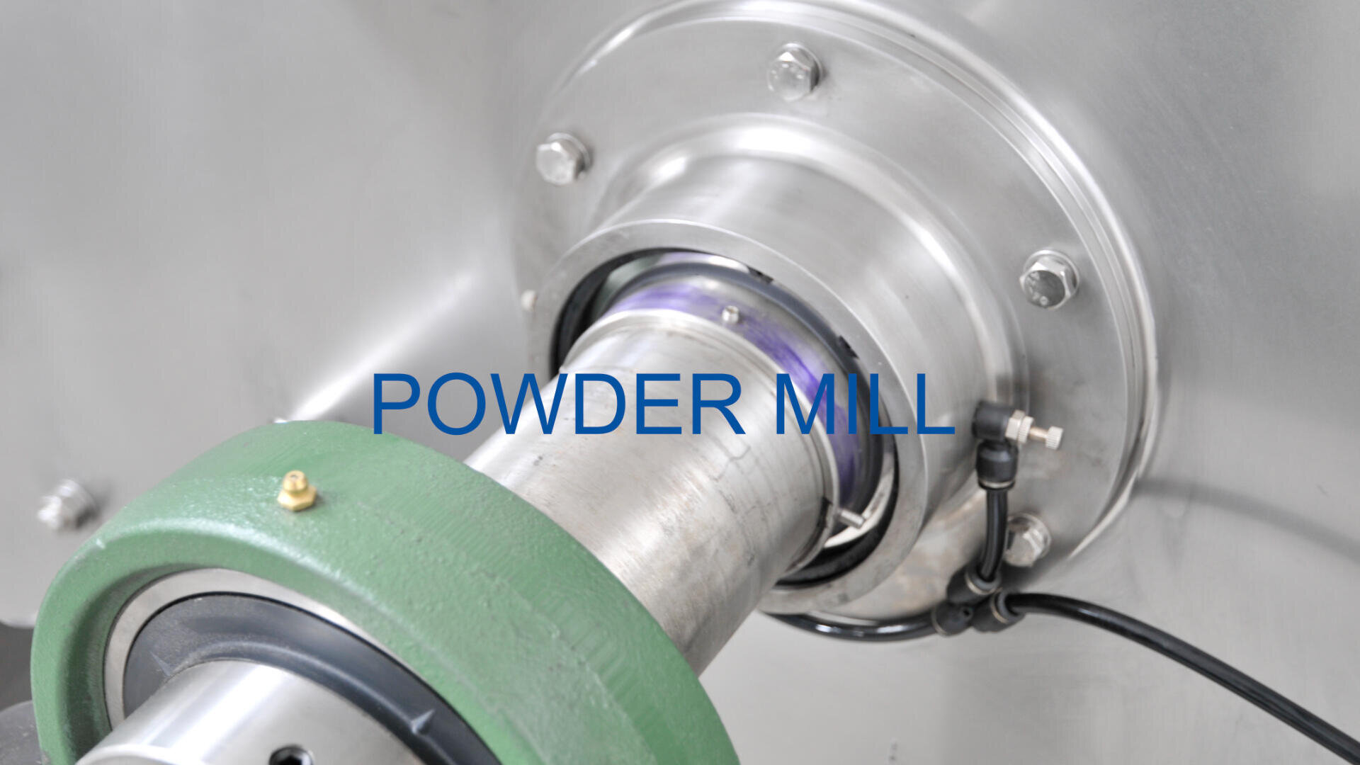 Close-up view of a metallic powder mill machine with bolts, wiring, and a green component, labeled POWDER MILL in blue text at the center.