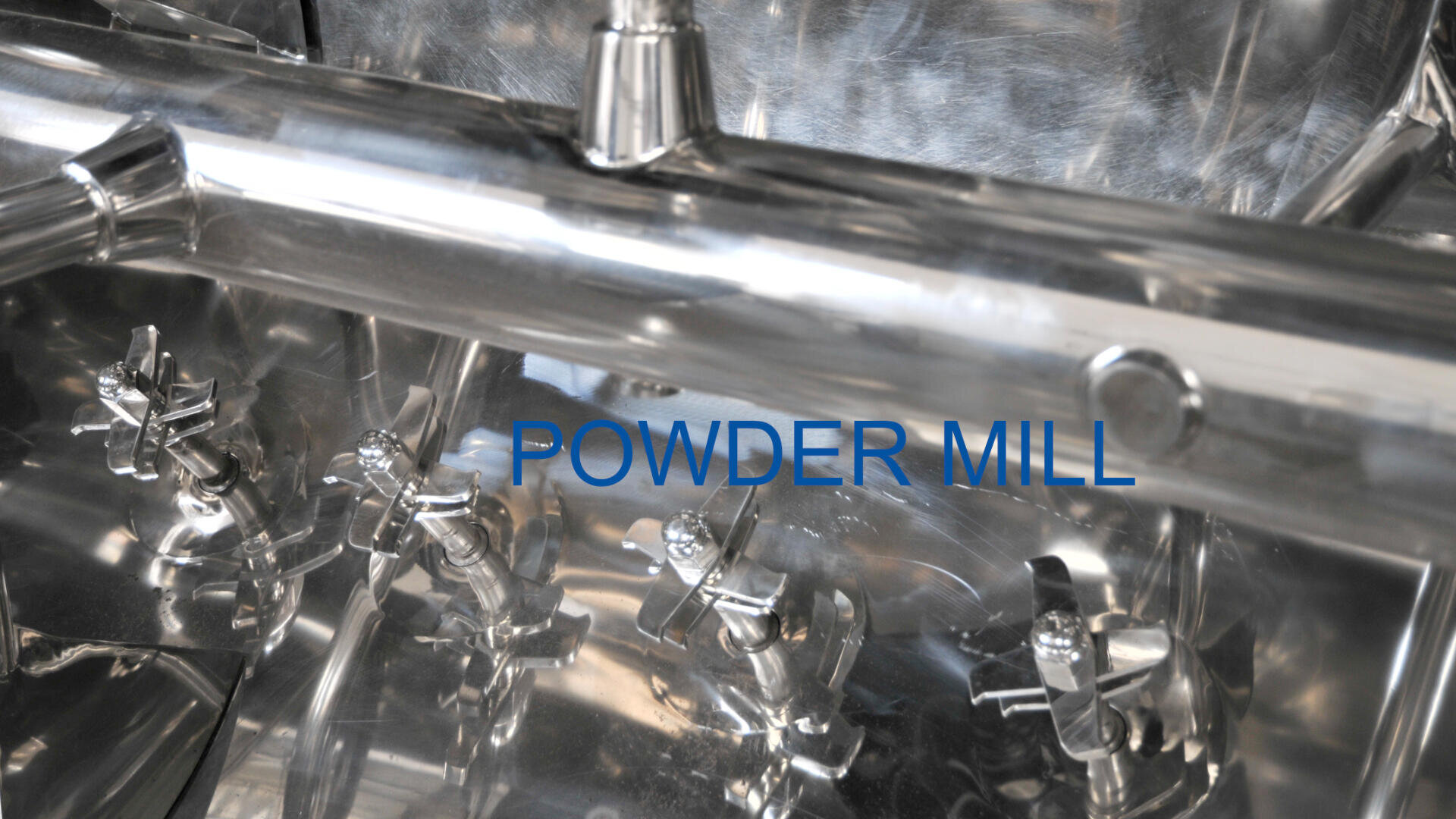 Close-up view of shiny metallic industrial machinery with multiple valves and the words POWDER MILL in blue text overlaid on the image.