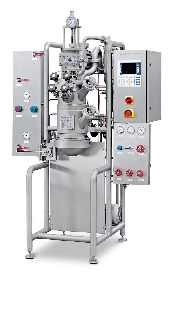 Ein industrieller Reaktorbehälter aus rostfreiem Stahl mit verschiedenen Ventilen, Messgeräten, Rohren und einem Bedienfeld mit Tasten, Messgeräten und einer digitalen Anzeige, der für die chemische oder pharmazeutische Verarbeitung verwendet wird.