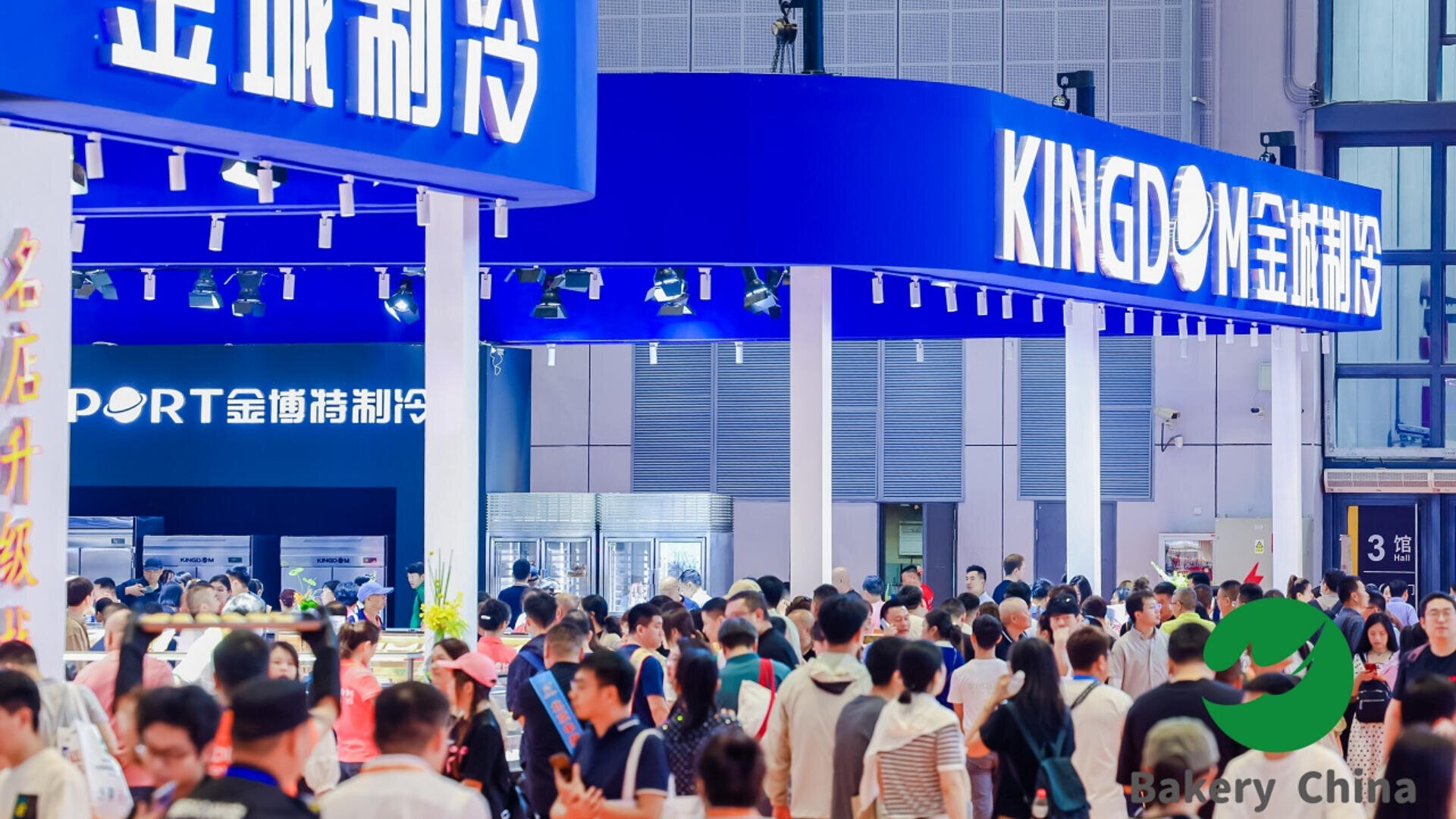 A large crowd attends an indoor exhibition with blue booths and signs displaying Chinese and English text. In the corner, a green Bakery China logo is visible.