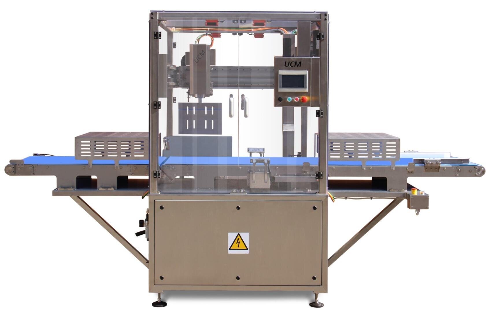 Automated industrial packaging machine with conveyor belt, transparent protective cover, control panel with buttons and safety warning sign on the front.
