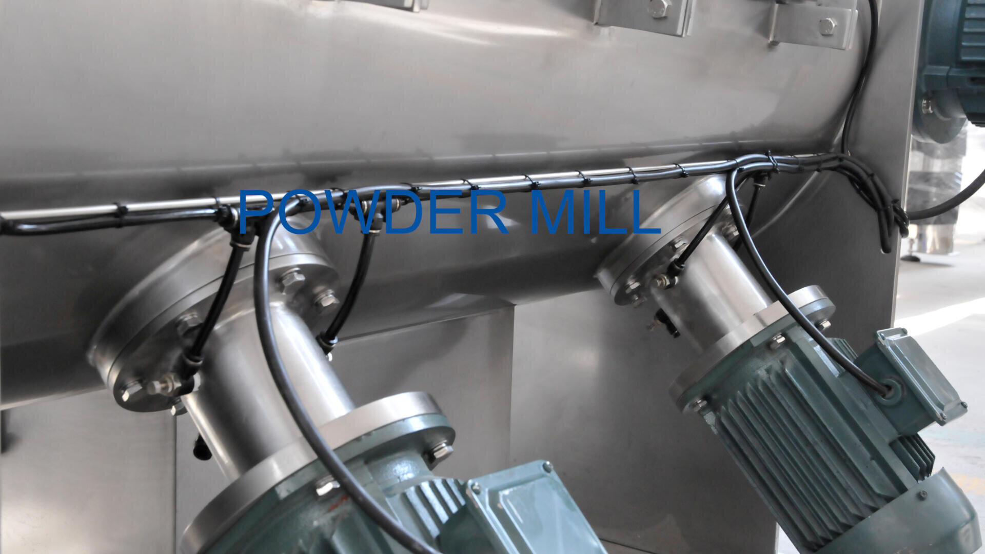 Close-up view of industrial equipment with two large motors attached to metal pipes. The words POWDER MILL are displayed in blue text across the image.