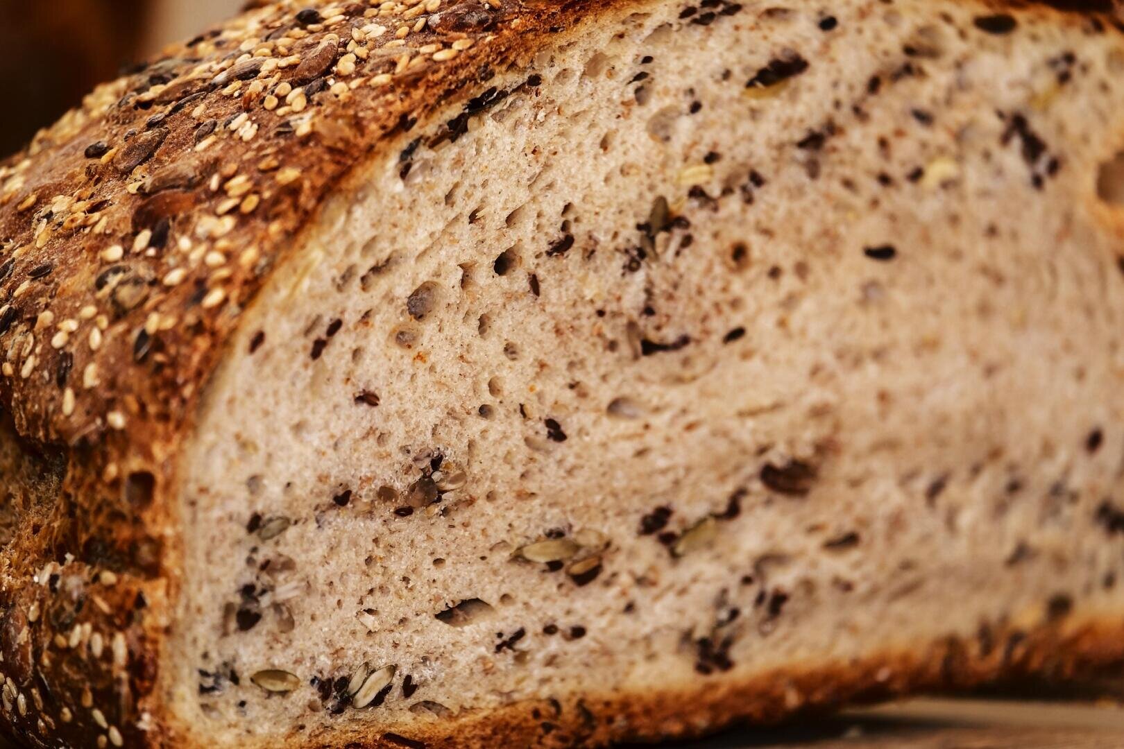 Close-up of a sliced piece of multigrain bread showing its textured, airy interior with visible seeds and grains embedded throughout the crust and crumb.