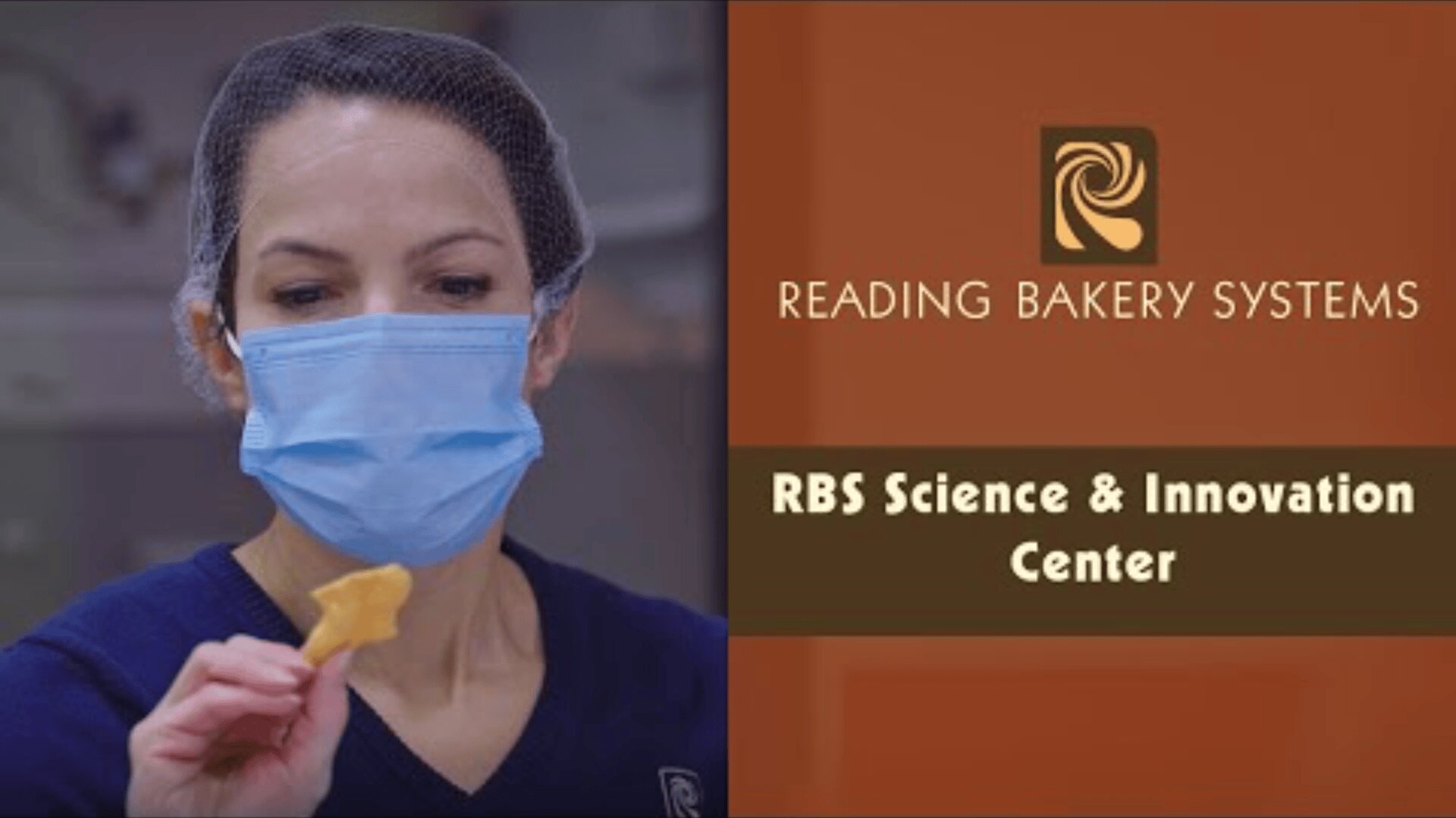 Eine Person, die ein Haarnetz, eine Maske und einen Laborkittel trägt, prüft einen Chip. Daneben steht ein Schild mit der Aufschrift Reading Bakery Systems RBS Science & Innovation Center und dem Firmenlogo.