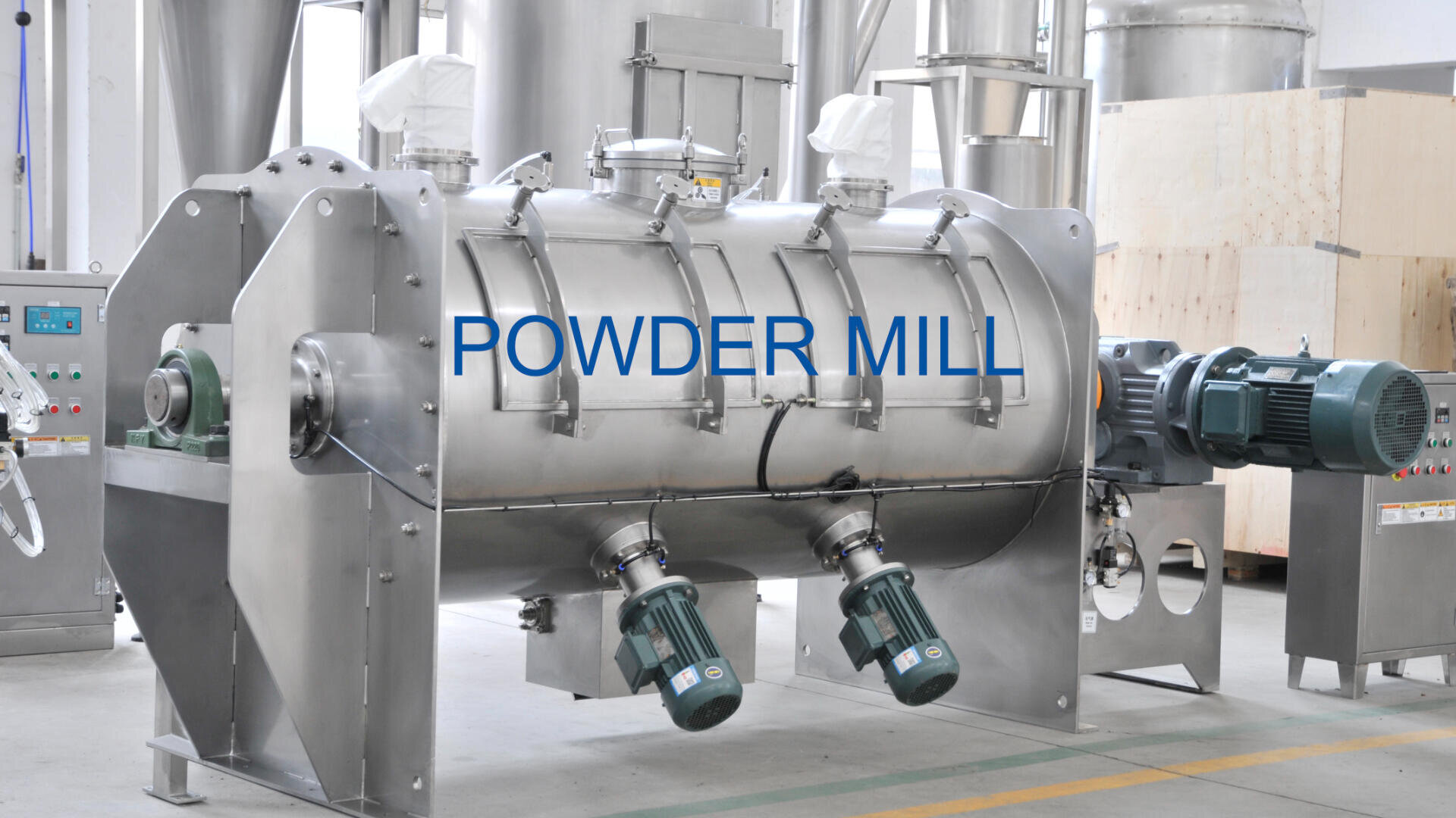 A large industrial stainless steel powder mill machine with two motors attached, set in a factory environment. The words POWDER MILL are labeled on the front of the machine.