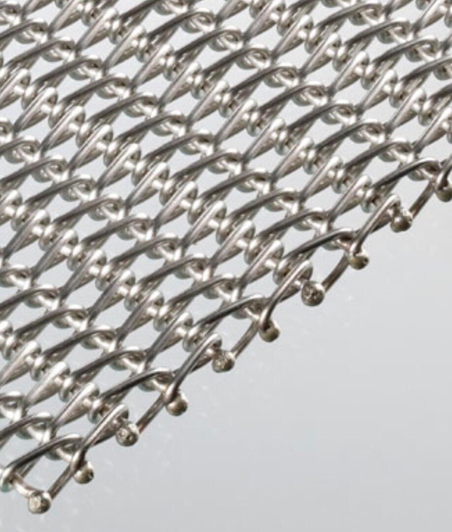 Nahaufnahme von ineinander verwobenen Metalldrähten, die eine flexible, netzartige Struktur bilden, die vor einem hellen Hintergrund silbern glänzt.