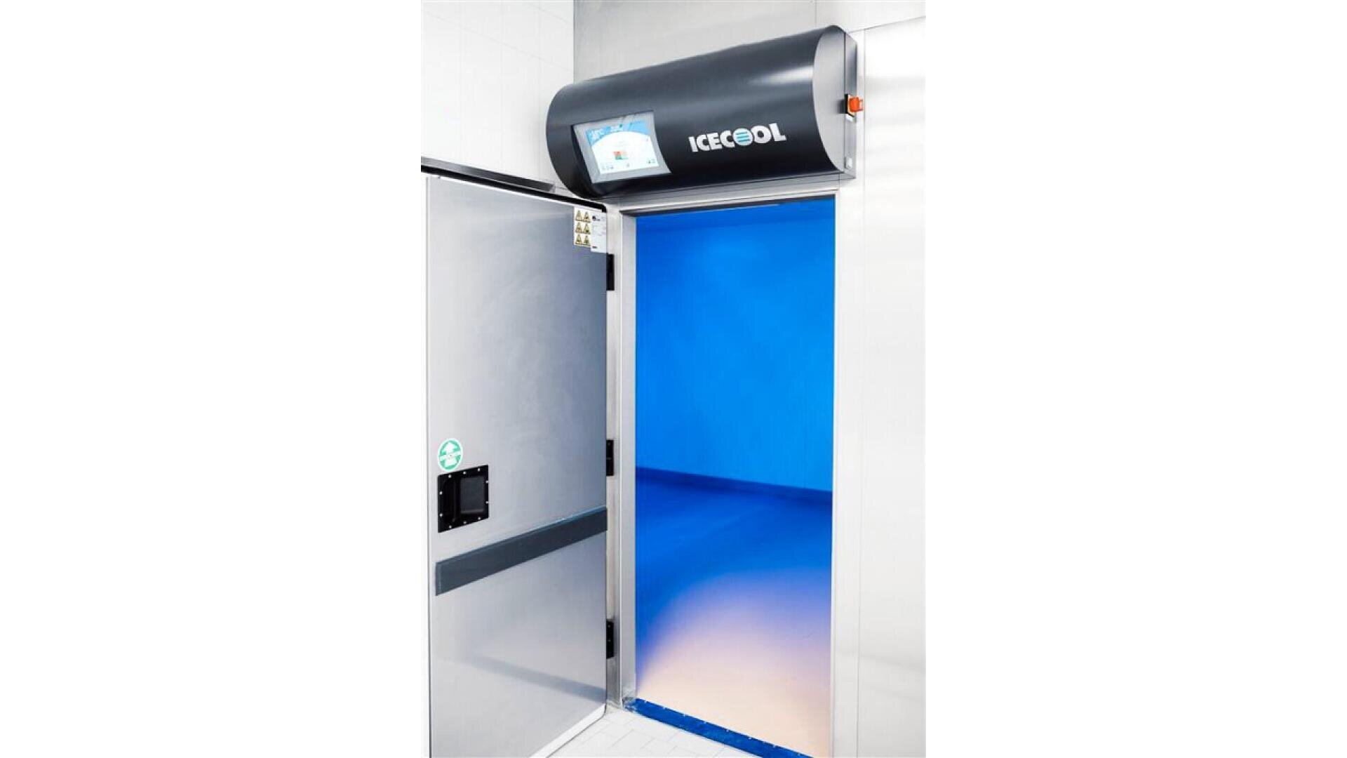 A stainless steel industrial cold room door labeled ICECOOL is open, revealing a blue-lit interior with clean, smooth floors and walls. A control panel screen is mounted above the doorway.