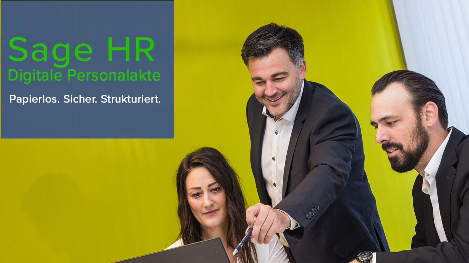 Drei professionell gekleidete Personen, zwei Männer und eine Frau, arbeiten gemeinsam lächelnd an einem Laptop. Auf einem grün-blauen Banner steht: Sage HR Digitale Personalakte. Papierlos. Sicher. Strukturiert.