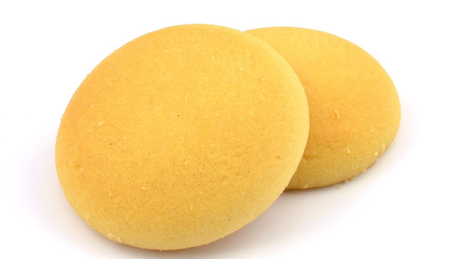 Two round, golden yellow cookies with a smooth, slightly crumbly surface are placed on a white background.