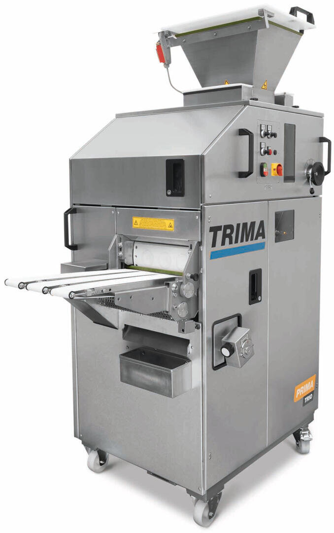 A large industrial bread dough divider and rounder machine by Trima, with a metal body, control panel, hopper on top, conveyor belt, and wheels for mobility.